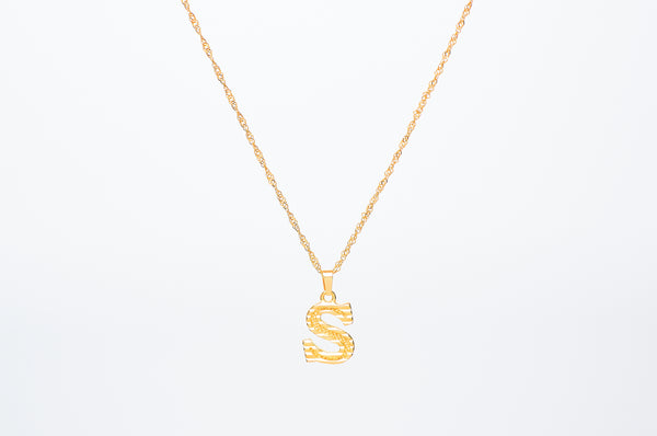 Initial necklace. Get your initial on a capital letter charm with line detailing. Crafted onto our Singapore chain necklace. Chain Length: 45cm. Pendant size 1.4cm. Made with stainless steel plated with 18K Gold. Dainty jewelry aesthetic with statement charm.